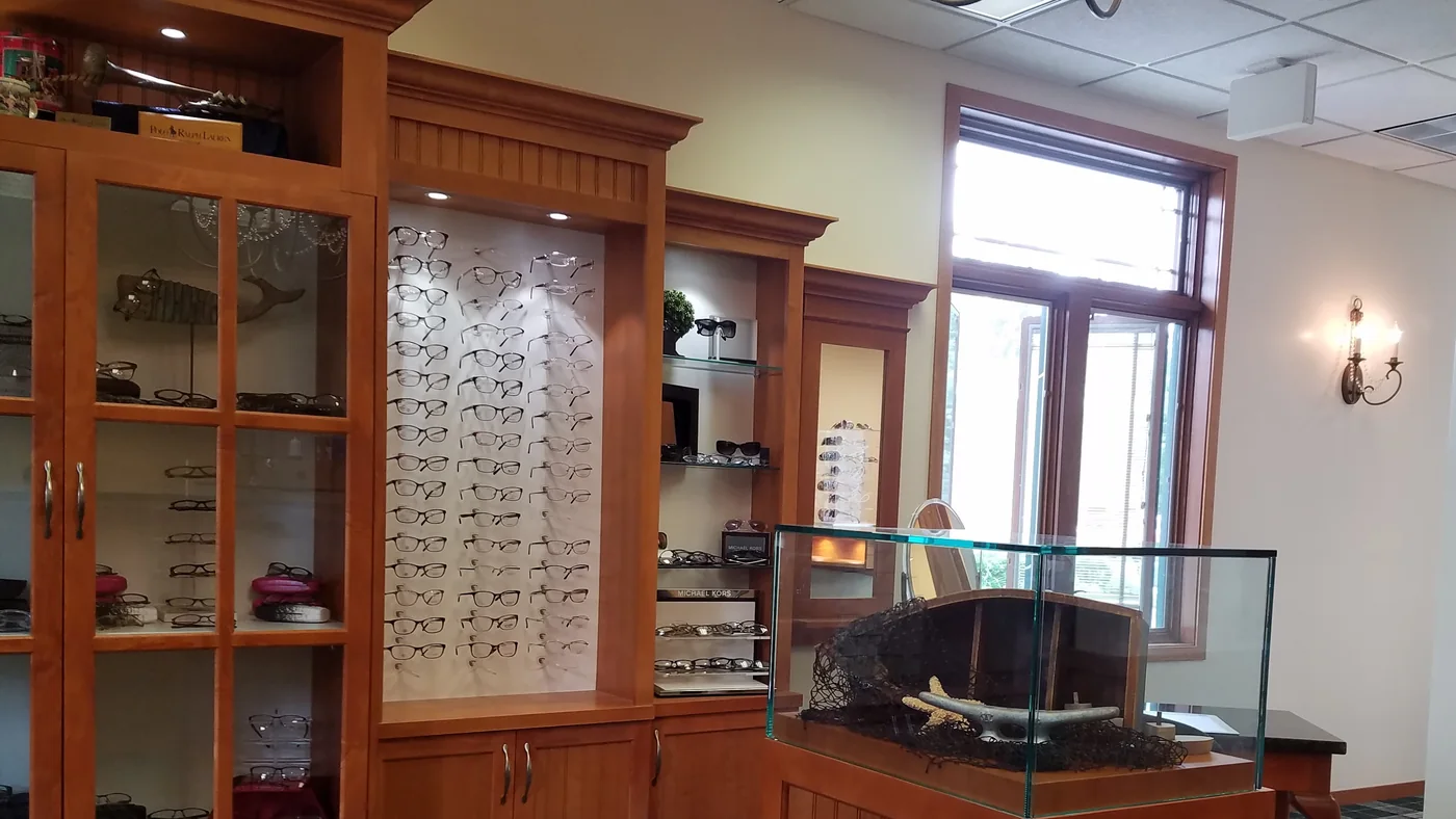 The optical at Evergreen Eye Care: cherry display cabinetry, a lit wall of frames and glass cases.