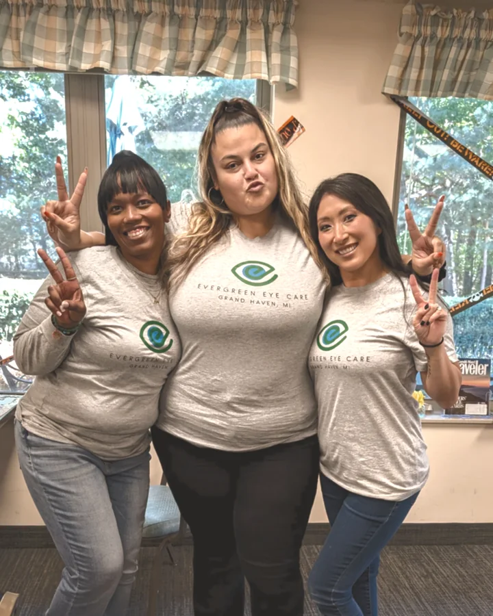 Three members of the Evergreen Eye Care team in branded shirts at the practice.